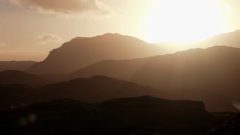 Ein-Langsamer-Schwenk-Nach-Links-Eines-Intensiven-Goldenen-Sonnenuntergangs,-Der-Eine-Umrissene-Berglandschaft-Im-Schottischen-Hochland-In-Abendlicht-Taucht