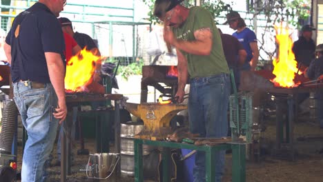 Blacksmith-craftsmen-hammering-hard-on-burning-hot-metal,-forging-and-shaping-the-piece,-crafting-horseshoe-at-annual-agricultural-competition-at-Ekka,-Royal-Queensland-Show,-Brisbane-city