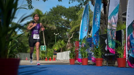 Slow-motion-of-a-female-young-athlete-in-a-purple-suit-running-to-the-finish-line-at-a-triathlon-competition