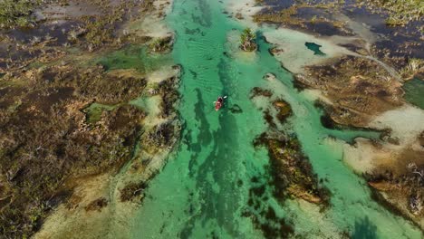 Flying-above-a-inflatable-canoe,-through-the-Bacalar-rapids,-in-sunny-Mexico---Aerial-view