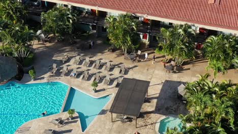 Swimming-pool-at-Double-Tree-resort-hotel-with-guests-enjoying-the-day,-Aerial-looking-down-shot