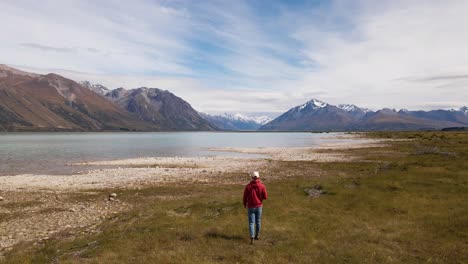 Person-from-behind-walking-along-picturesque-alpine-lake-in-New-Zealand