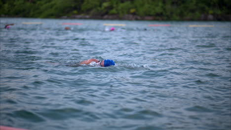 Male-athlete-swimming-freestyle-wearing-a-cap-and-goggles-in-the-sea-at-a-triathlon
