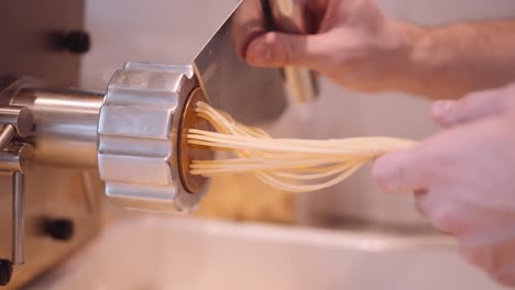 Männlicher-Koch-Begleitet-Und-Schneidet-Die-Langen-Spaghettistränge-Aus-Der-Nudelmaschine