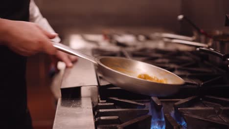 Cook-shakes-the-silver-pan-with-pasta-back-and-forth-while-the-pasta-cooks-on-the-fire