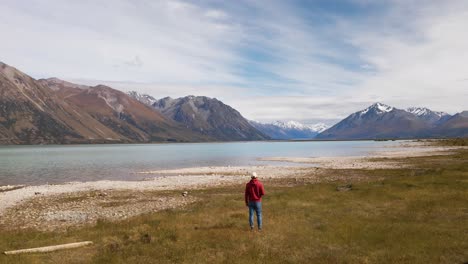Persona-Desde-Atrás-Caminando-Hacia-El-Hermoso-Lago-Glaciar-Frente-Al-Pintoresco-Paisaje-Alpino