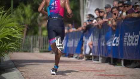 Latin-male-athlete-running-passing-by-a-crowd-of-spectators-cheering-the-participants-at-a-triathlon-competition