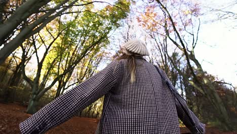 Low-angle-shot-of-a-Caucasian-woman-turning-around-while-admiring-her-surroundings,-in-a-park-in-autumn-in-Amsterdam