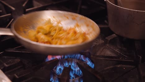 Pasta-is-shaken-in-a-silver-pan-on-the-gas-stove-in-a-restaurant-kitchen