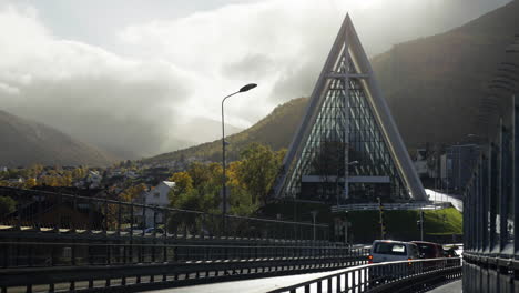 Coches-Conduciendo-El-Puente-Tromso-Sobre-El-Río-Con-El-Telón-De-Fondo-De-La-Catedral-ártica