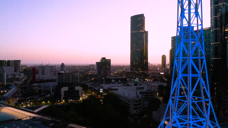 Melbourne-Art-Spire-Mit-Blauem-Neonlicht-Hervorgehoben,-Das-Gegen-Die-Wunderschöne-Skyline-Der-Stadt-In-Der-Dämmerung-Leuchtet