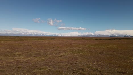 Endless-dry-plains-in-sunshine-with-snow-capped-mountains-in-the-distance