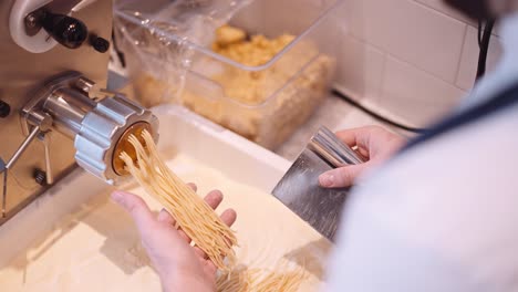 El-Cocinero-Macho-Corta-Las-Largas-Hebras-De-Espagueti-De-La-Máquina-De-Pasta