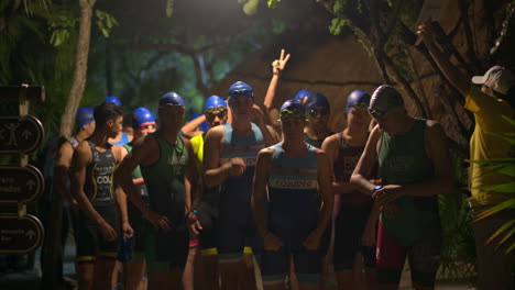 Group-of-young-athletes-ready-to-start-the-swimming-stage-of-a-triathlon-wearing-caps-and-goggles-exited-and-nervous