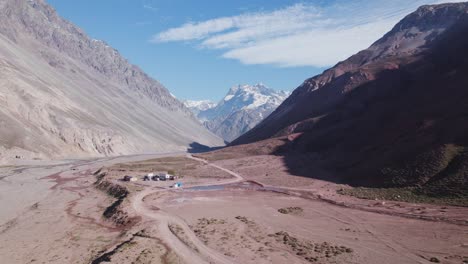 Aerial-View-Of-Unpaved-Road-And-Volcan-River-In-Andes-Mountain-Range-In-San-Jose-de-Maipo,-Chile