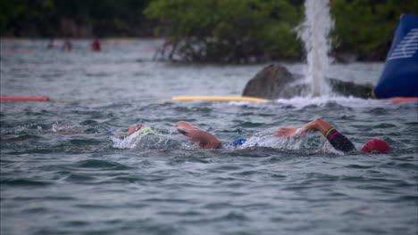 Group-of-female-athletes-of-various-ages-swimming-freestyle-wearing-cap-and-goggles-in-the-morning-at-a-triathlon-competition