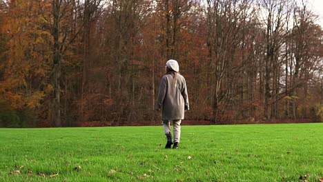 Shot-of-a-Caucasian-woman-walking-and-looking-around-an-autumn-park-in-Amsterdam,-in-slowmotion