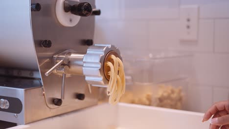 Long-strands-of-spaghetti-comming-out-of-the-pasta-machine