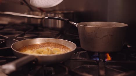 Cocinero-En-Un-Restaurante-Quita-La-Pasta-De-La-Sartén-A-Fuego-Alto-Y-Saca-La-Pasta-En-La-Sartén-Mientras-El-Fuego-Está-Encendido