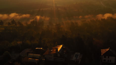 An-incredible-sunrise-shot-over-a-house-with-solar-panels,-flying-into-a-foggy-forest-nearby,-Republic-of-Moldova