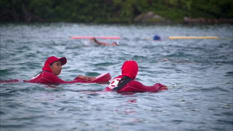 Two-latin-female-lifeguards-swimming-along-the-athletes-competitors-at-a-triathlon
