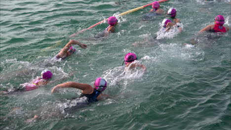 Gruppe-Junger-Lateinamerikanischer-Mädchen-Im-Teenageralter-Teilnehmer-Teilnehmer-Wettbewerber,-Die-Ins-Wasser-Eintreten,-Um-Den-Triathlon-Wettbewerb-Zu-Starten