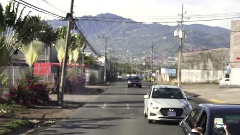 Cars-driving-on-one-way-street-with-mountains-behind,-Slow-Motion-looking-back-shot