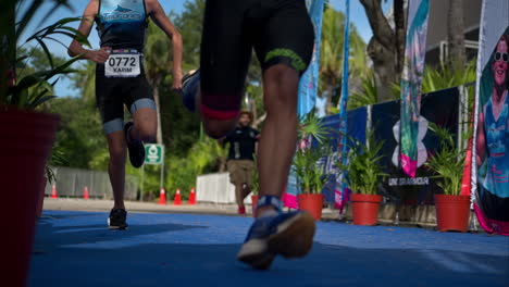 Slow-motion-of-two-teenage-male-athletes-sprinting-racing-each-other-at-the-finish-line-of-a-triathlon-competition