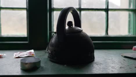 Slow-panning-shot-of-an-old-kettle-sitting-on-a-windowsill-in-a-remote-Scottish-highland-mountain-shelter-