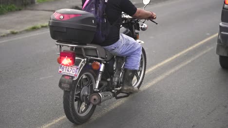 Man-riding-motorcycle-behind-SUV-car-in-the-middle-of-a-road,-Slow-motion-follow-behind-shot
