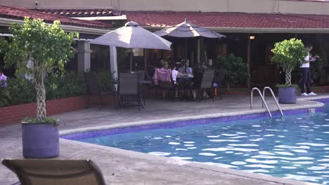 People-enjoying-a-cocktail-brunch-at-Double-Tree-resort-hotel-pool-area,-Wide-medium-shot
