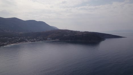 Aerial-Over-Calm-Ionian-Sea-With-Himare-Coastline-And-Mountains-In-Background-In-Albania