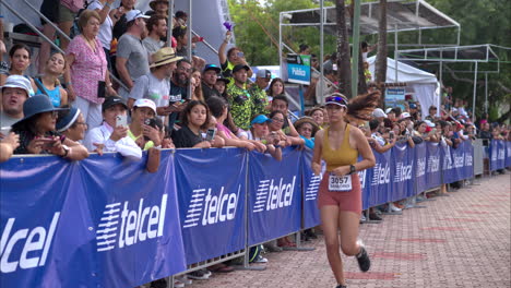 Atleta-Femenina-Corriendo-Trotando-En-Una-Competencia-De-Triatlón-Junto-A-Los-Espectadores-Animándolos