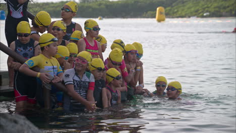Gruppe-Junger-Lateinamerikanischer-Kinder-Teilnehmer-Teilnehmer-Teilnehmer-Warten-Auf-Den-Start-Des-Triathlon-Wettbewerbs-Und-Sind-Bereit,-Ins-Wasser-Zu-Gehen