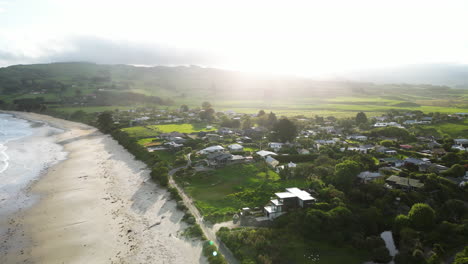 Aerial-view-of-Huriawa,-commonly-known-as-Huriawa-Peninsula-or-Karitane-Peninsula,-warm-sunset-golden-hours-light-with-scenic-green-hills-and-coastline