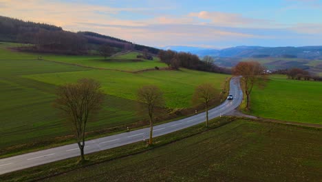 Aerial-View-of-Bruchhausen-an-den-Steinen-Surrounded-by-Beautiful-Landscape-with-Cars-Driving-on-a-Small-Road-During-Early-Morning-Light