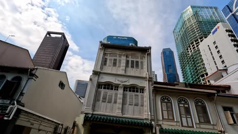 Traditional-Buidings-and-Modern-Skyscaper-in-Singapore,-Low-Angle-Wide-Pan
