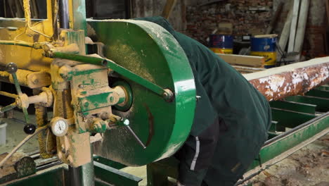 Mechanic-repairs-dirty-bandsaw-machine-in-sawmill-for-log-sawing-into-planks