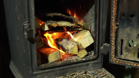 Burning-firewood-in-small-metal-fireplace-for-heating,-close-up-view