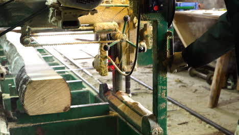 Worker-operating-with-wood-processing-equipment-in-sawmill,-sawing-aspen-tree-log-on-bandsaw