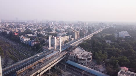 Cinematic-aerial-shot-revealing-newly-built-cable-styled-Majerhat-bridge-road-in-the-center-of-Kolkata,-metro-station-building-construction-close-to-Majerhat-railway-station-and-cityscape