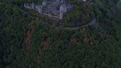 Bourscheid-Castle-on-forest-hill-top-in-Luxembourg-on-cloudy-grey-day,-aerial