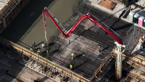 Construction-Workers-During-Concrete-Pouring-With-Boom-Concrete-Pump-At-The-Site