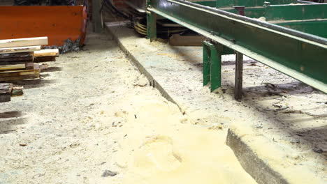 Sawdust-and-dirty-floor-in-sawmill,-handheld-dolly-out