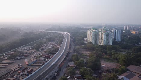 Cinematic-revealing-shot-of-newly-built-Majerhat-over-bridge-road-with-Iron-Garage-on-left-side-of-it-and-Highrise-buildings-on-the-other-side,-Aerial-shot