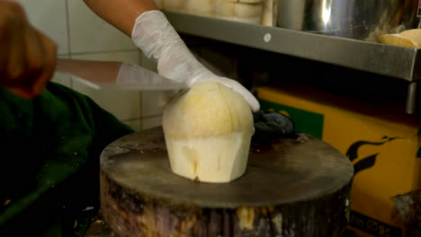 Thailand,-Bangkok---13-August-2022:-Unrecognizable-man-cutting-green-peeled-coconut-and-spilling-the-coconut-water-into-a-pot
