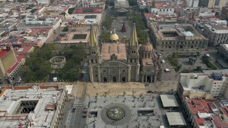 Drone-descends-in-front-of-historic-Guadalajara-with-people-walking,-Catholic-Church-of-Mexico
