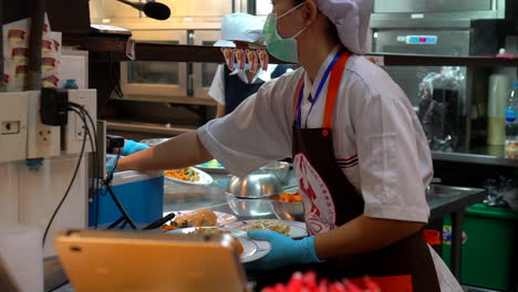 Thailand,-Bangkok---18-August-2022:Woman-waiter-in-a-restaurant-adding-chili-to-pad-thai-dishes-and-serving