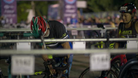 Senior-male-athlete-wearing-a-helmet-pumping-air-into-his-bike's-wheel-early-in-the-morning-before-the-competition-starts