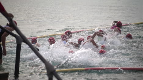 Group-of-latin-teenage-boys-contestants-participants-competitors-entering-the-water-to-start-the-triathlon-competition
